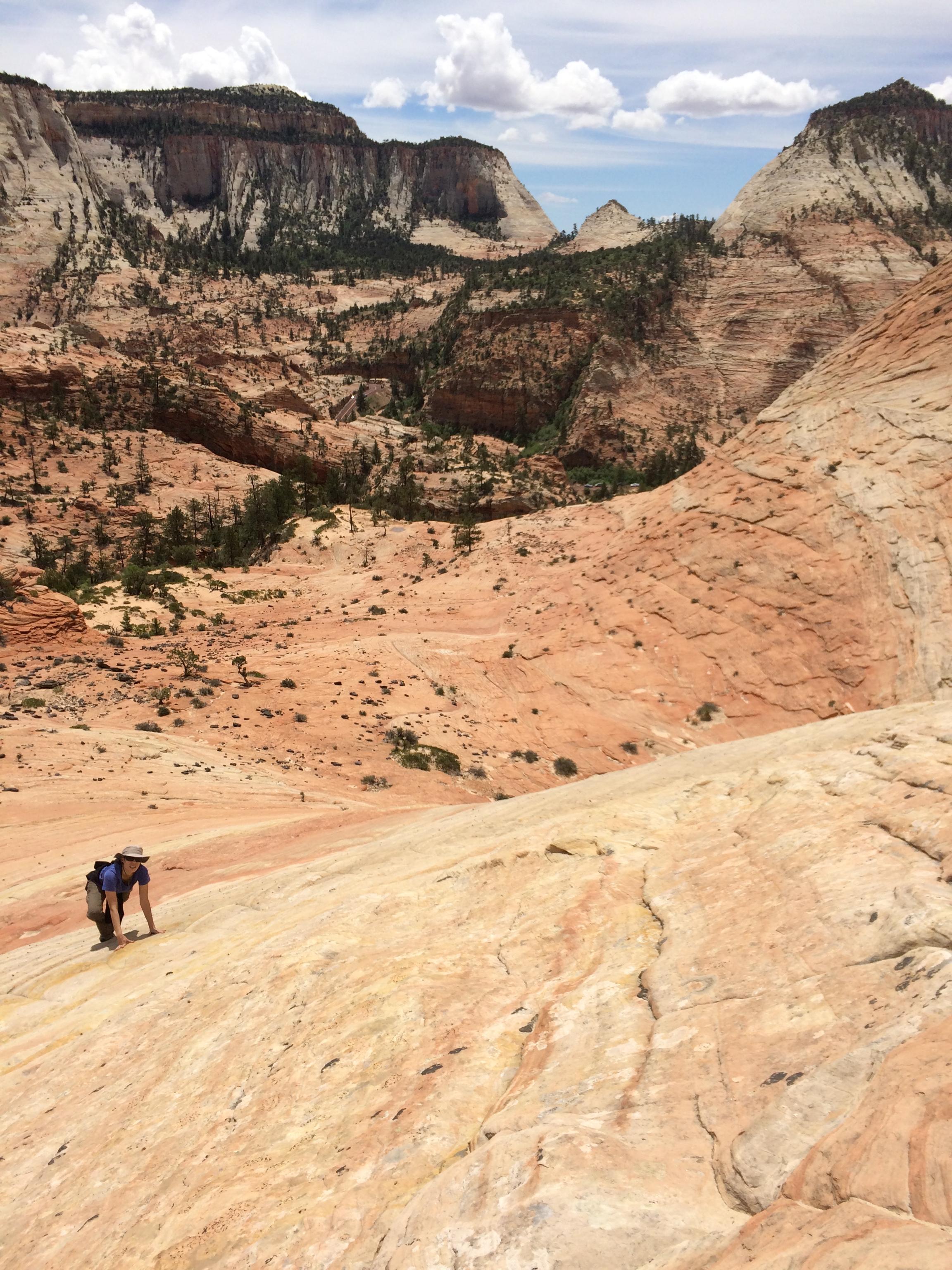 person walking on all fours up steep slickrock